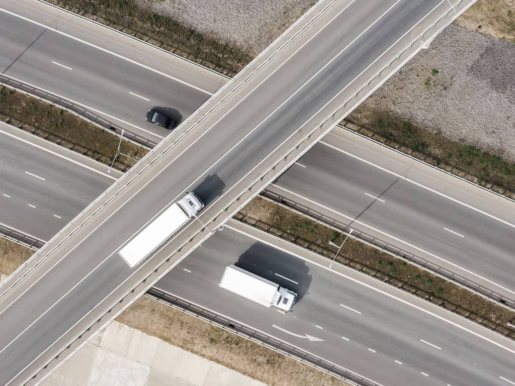 two trucks drive on and under overpass on freeway 1